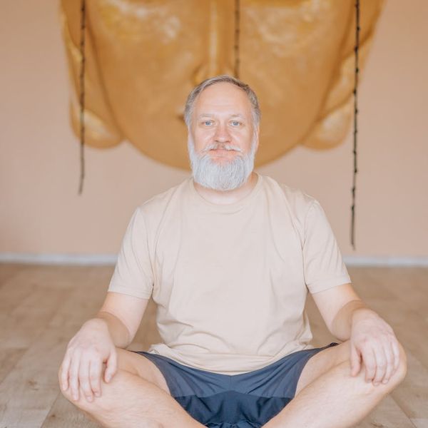 Person sitting in a calm lotus yoga pose in a bright, clean space.