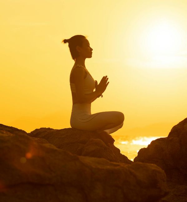 Silhouette of a person in a strong warrior yoga pose at sunset.